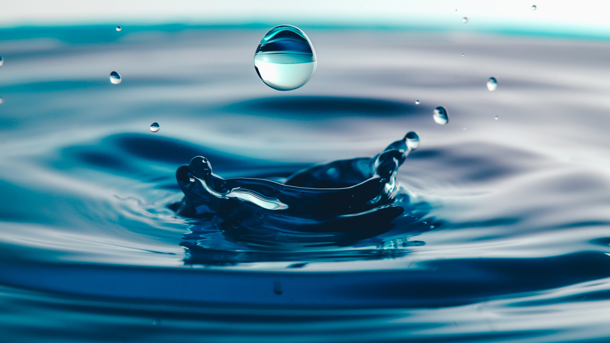 Image of a drop of water falling about to hit the water just after one drop has splashed.