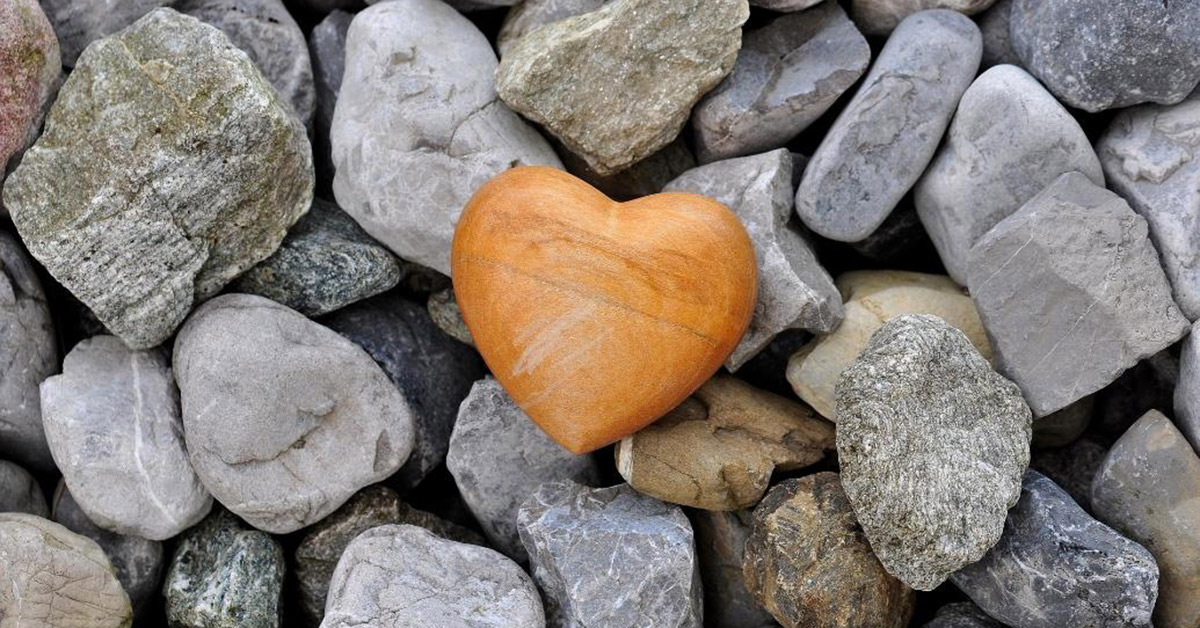 Sermon, Deeds of Welcome. Photo of gray rocks with an orange heart shaped rock in the center.