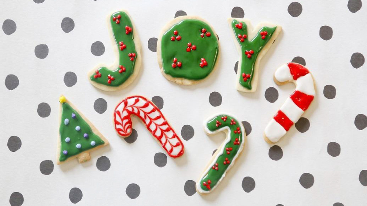 J-O-Y Christmas cookies as well as a tree and three candy cane cookies on a polka-dot background.