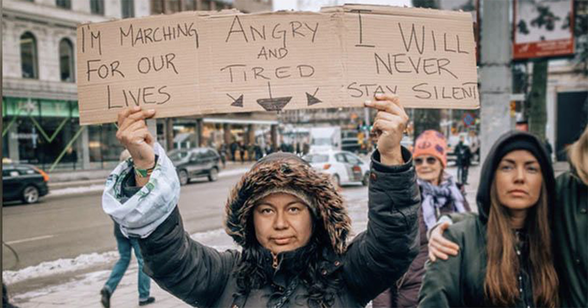 Women in winter coat holding a protest sign